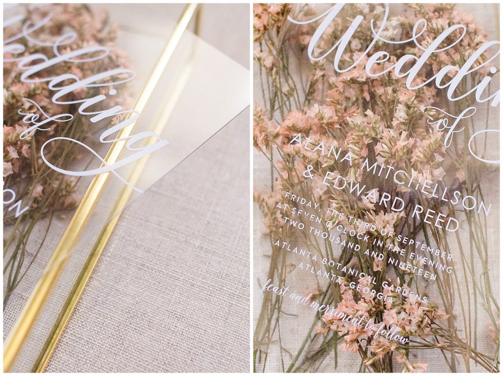 clear wedding invitation over wildflowers and gold tray
